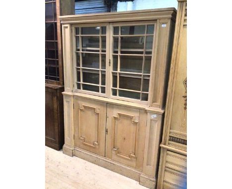 A 19thc stripped pine bookcase, the cushion cornice above two glazed doors enclosing two shelves, two geometric panel doors u