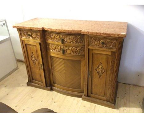 An early 20thc continental inverted break centre bow front credenza, the marble top over four drawers with floral carving and