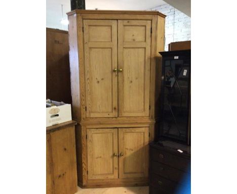 A 19thc pine floor standing corner cupboard the projecting cornice above two panelled doors enclosing two shelves with two fu