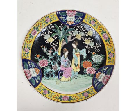 Early 20th century Chinese famille noir charger, decorated with two ladies in a garden before rockwork and flowering prunus a