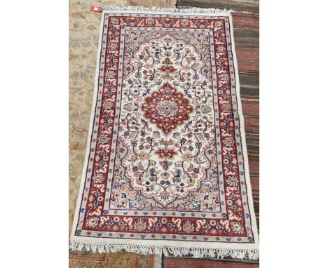 Indian cream ground wool pile rug, central floral medallion within stylised floral panel with spandrals, floral and herati bo
