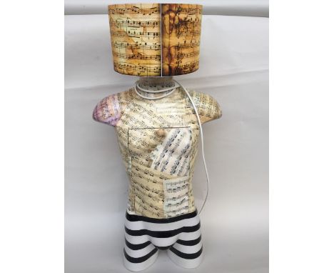 A three quarter length torso lamp with cupboard with internal shelf and drop flap front, decorated with musical scores and bl