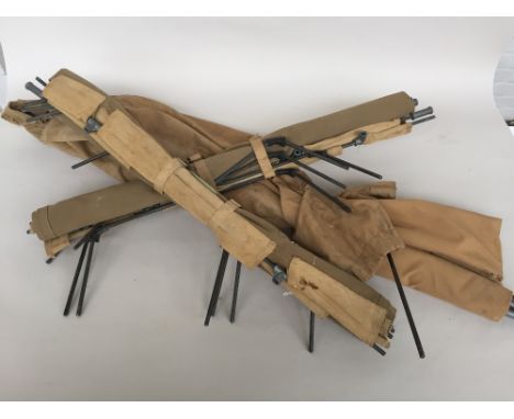 Three roll up canvas army camp beds with metal supports and a carry case