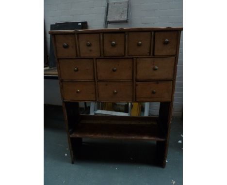 A wooden pine drawer unit with eleven drawers over one shelf, three hooks on the left side  38 x 89 x 114cm