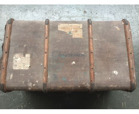 A vintage wood-bound canvas cabin trunk bearing luggage labels, straps and inside compartment , leather handles on the side, 