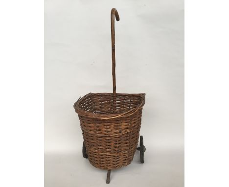 A vintage wicker shopping trolley with cane walking stick handle, three legged stool, a wooden and iron shoe mould and a vint