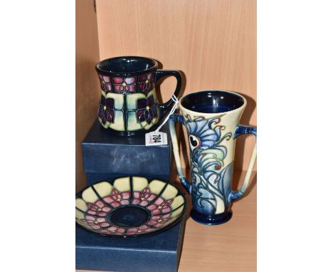 THREE MOORCROFT POTTERY ITEMS to include two boxed 'Violet' patterned items comprising a mug and a saucer, designed by Sally 