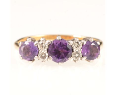 An amethyst and diamond dress ring, three round brilliant cut amethyst, claw set and spaced by two pairs of brilliant cut dia