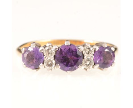 An amethyst and diamond dress ring, three round brilliant cut amethyst, claw set and spaced by two pairs of brilliant cut dia