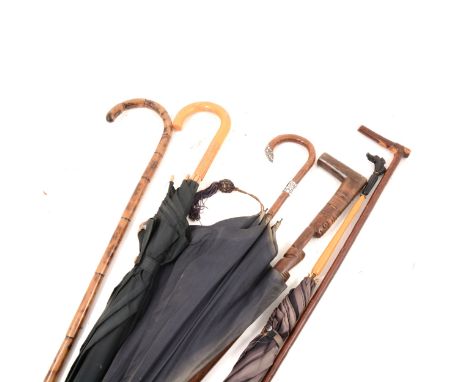 A vintage umbrella with ebony handle and carved elephant finial, 90cm; another umbrella with white metal mount and finial; an