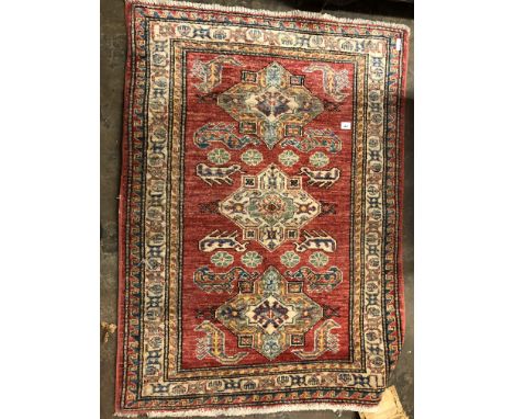 EARLY 20TH CENTURY GEOMETRIC PATTERNED WOOLEN CARPET ON A RED GROUND