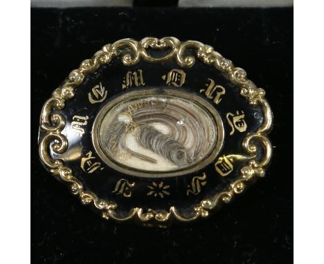A Victorian yellow metal and black enamel mourning brooch encasing a lock of hair and inscribed In Memory Of. Engraved verso 