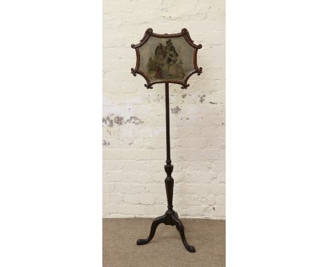 A Victorian mahogany pole screen with carved scrollwork frame, needlework panel and raised on a tripod base.