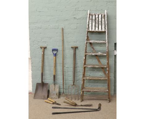 A pair of old wooden steps and a collection of garden tools.