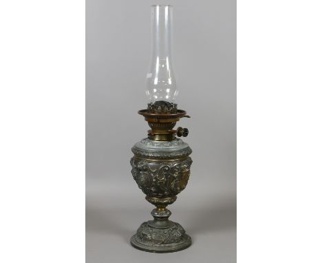 A Victorian oil lamp with cast metal base decorated with scrolline strapwork.