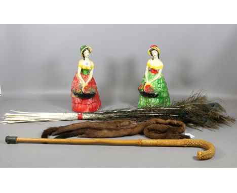 A pair of painted plaster cast figurines, a walking stick, mink fur stole and a bunch of peacock feathers.