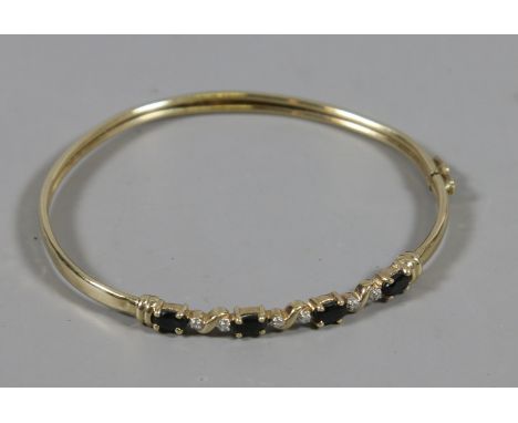 A 9 carat gold bangle set with ovoid sapphires interspersed with pairs of diamonds, 4.2 grams. 