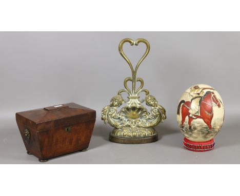 A Regency mahogany tea caddy, a brass and iron doorstop and a painted ostrich egg.