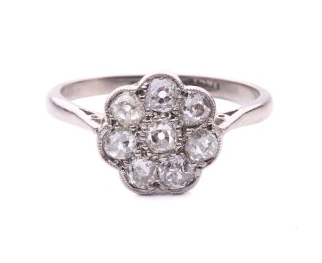 A diamond flowerhead cluster ring, scintillating with eight old-cut diamonds in a scalloped mount with millgrain details, tap
