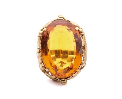 A citrine solitaire ring set with a large oval-cut citrine measuring 26mm x 18.5mm x 9mm, to a claw setting, surrounded by a 