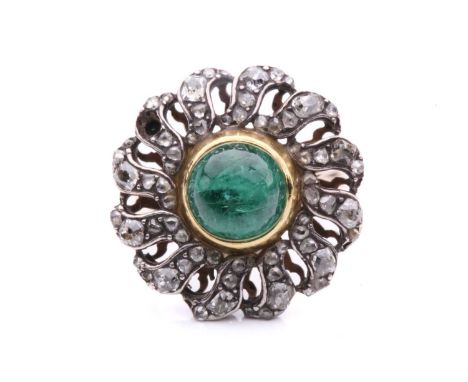 An emerald and diamond flowerhead cluster ring, to the centre a round high-domed emerald cabochon in a closed back collet, su