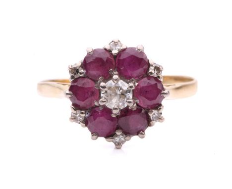 A ruby and diamond cluster ring, set with a central round brilliant cut diamond encircled by rubies and single cut diamond po