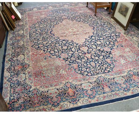 Kirman Carpet, the indigo field of scrolling vines around an ivory medallion framed by raspberry spandrels and meandering vin