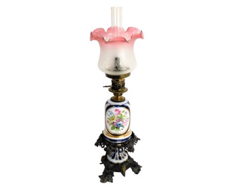 A Victorian oil lamp, with a pink and frosted etched glass shade, a porcelain central reservoir decorated with flowers, on a 