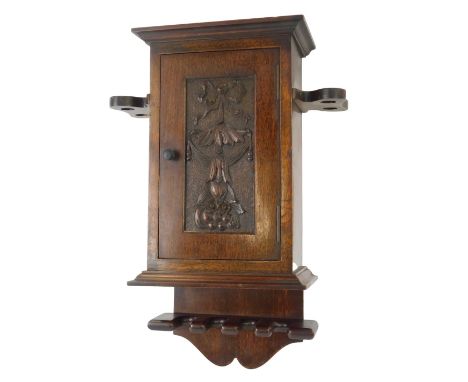 An early 20thC and later oak wall hanging pipe box, the top with an outswept pediment above a bow, fruit and floral carved do