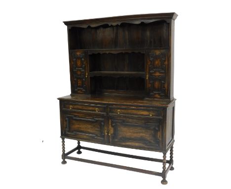 A 20thC oak dresser, the top with a moulded edge above one long shelf and two shorted shelves flanked by two panelled cupboar