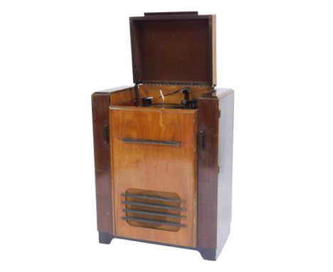 A mid century walnut and mahogany Bush RG4 radiogram, the hinged lid enclosing a Garrard Model RC65 turntable, over a fall en