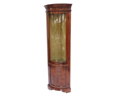 A 20thC mahogany bow front corner display cabinet, the top with a moulded edge, above a glazed door with cupboard to base, in