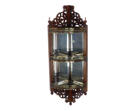 An Edwardian mahogany corner display shelf, the raised pierced back with urn finials, above a pierced brass shelf, above two 