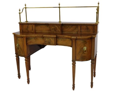 A George IV flame mahogany and ebony line inlaid inverted serpentine sideboard, with brass rail back surmounted by urn finial