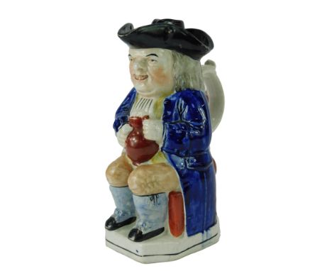 A 19thC pottery Toby jug, modelled as a seated gentleman wearing a tricorn hat, with a lid, holding a tankard containing beer