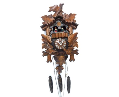 A 20thC oak cuckoo clock, with maple leaf and bird decoration, 25cm high, with weights and pendulum.