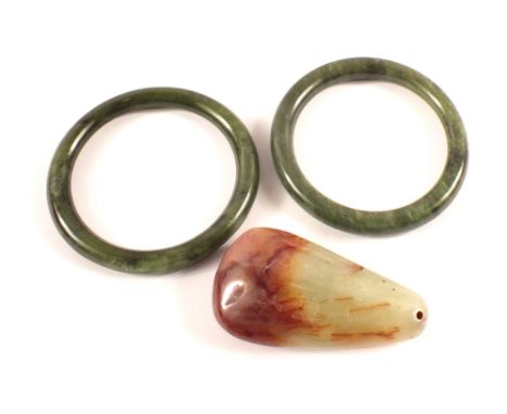 Two Chinese jade bangles and a pebble shaped pendant decorated with calligraphy