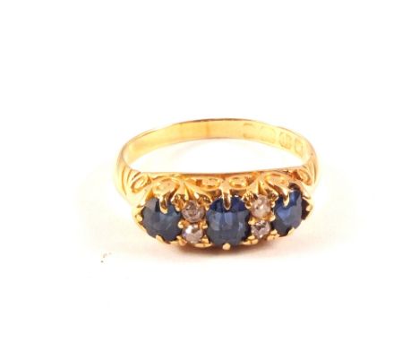 An 18ct gold three stone sapphire ring interspaced with small diamonds, size O