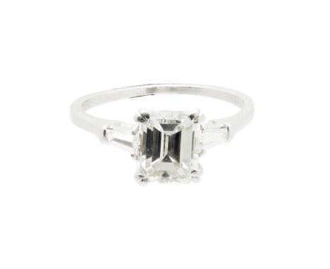 A single stone diamond ringclaw set with a trap cut diamond, each shoulder set with a tapered baguette cut diamond, to a plai