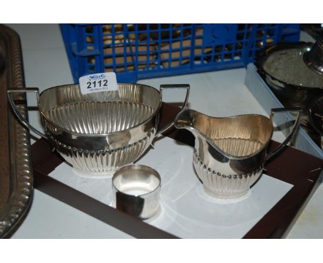 A silver plated Cream Jug and Sugar Basin and a metal Napkin Ring.