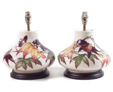 Pair of Moorcroft lamps, decorated with leaves and flora on an ivory colour ground, with original Moorcroft shades.The cerami