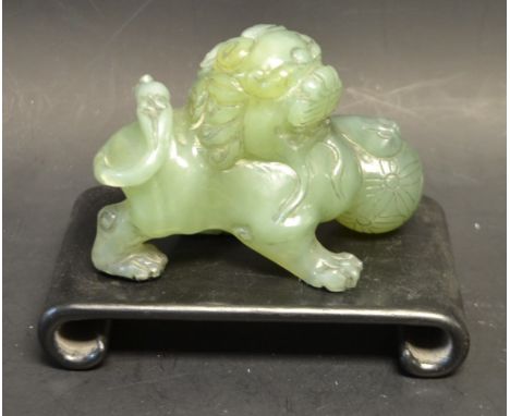 A Chinese jade Fo dog with ball, hardwood stand