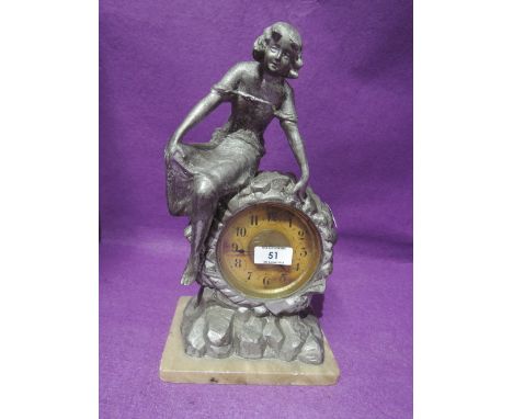 An early figural clock of lady perched on rocks cast in spelter in an art deco style