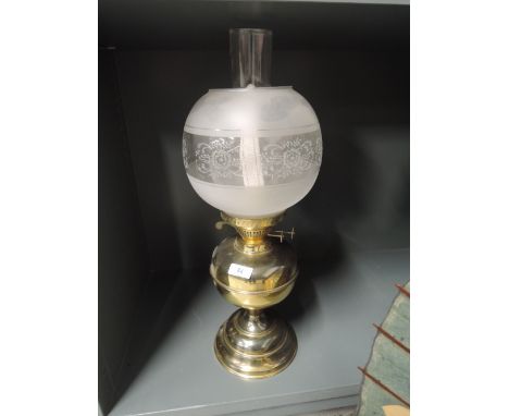 A vintage oil burning lamp with etched glass shade