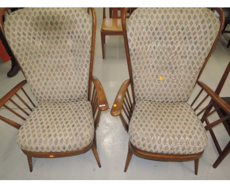 A pair of wing back arm chairs by Ercol in a medium stain 