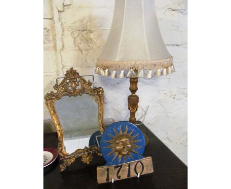 A gilt brass table lamp, a small gilt mirror and a sun plaque