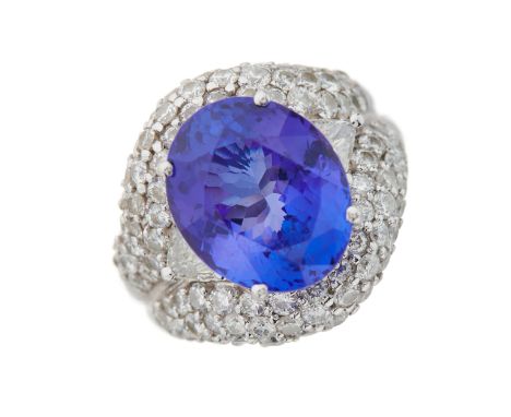 An 18ct gold oval-shape tanzanite cocktail ring, with triangular-shape diamond sides and pave-set diamond surround, tanzanite