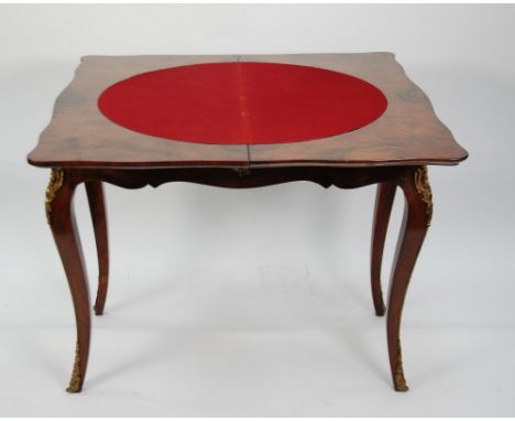 A MID VICTORIAN FIGURED WALNUT ORMOLU MOUNTED FOLD OVER SWIVELLING TOP CARD TABLE IN THE FRENCH TASTE, of serpentined outline