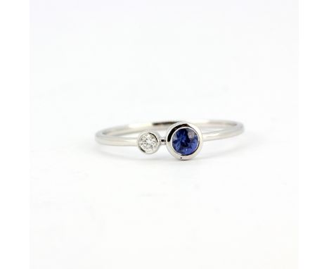 An 18ct white gold ring (stamped 750) set with a brilliant cut diamond and a sapphire, (N).