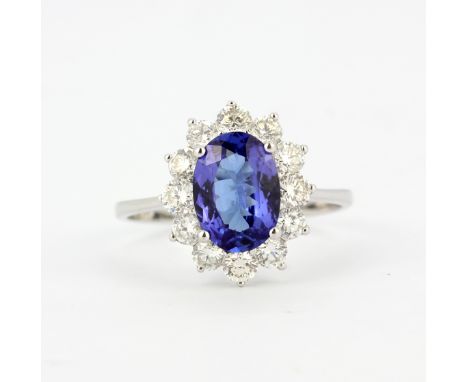 An 18ct white gold (stamped 750) cluster ring set with an oval cut tanzanite surrounded by brilliant cut diamodns, (P).